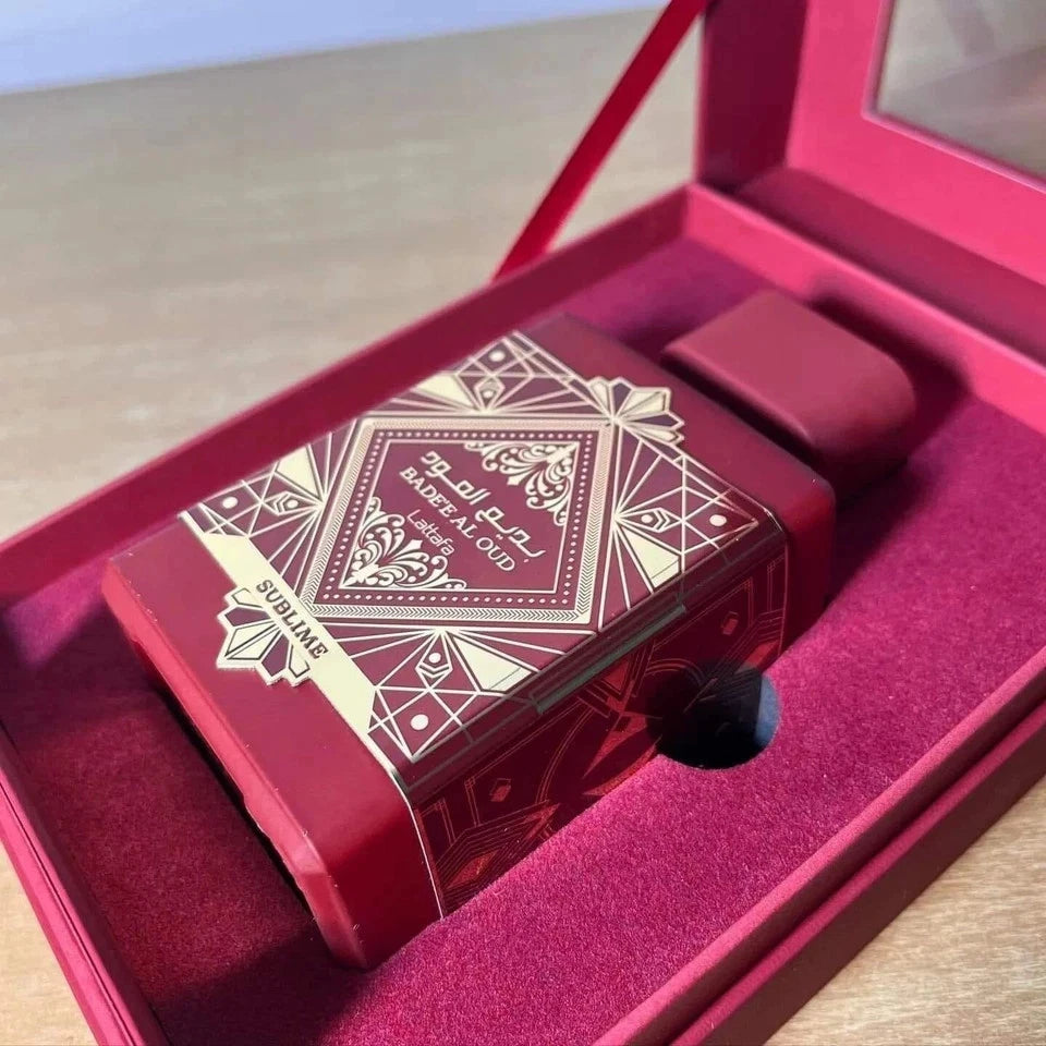 Red decorative item with gold patterns inside an open pink box on a wooden surface.
