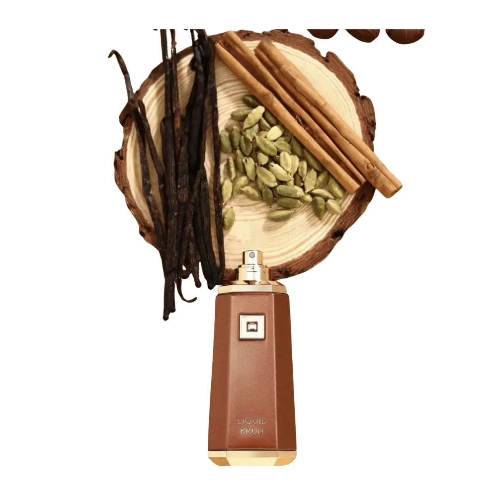Perfume bottle with vanilla beans, cinnamon sticks, and cardamom on a wooden platform