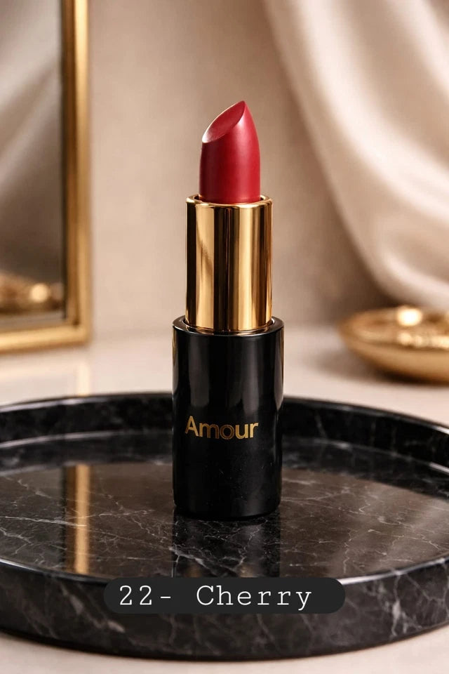 Red lipstick with gold cap and black body labeled 'Amour' on a marble surface.