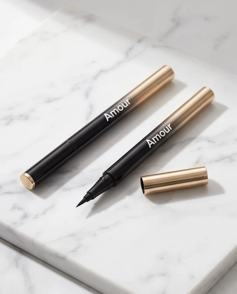 Two 'Amour' branded eyeliner pens on a marble surface