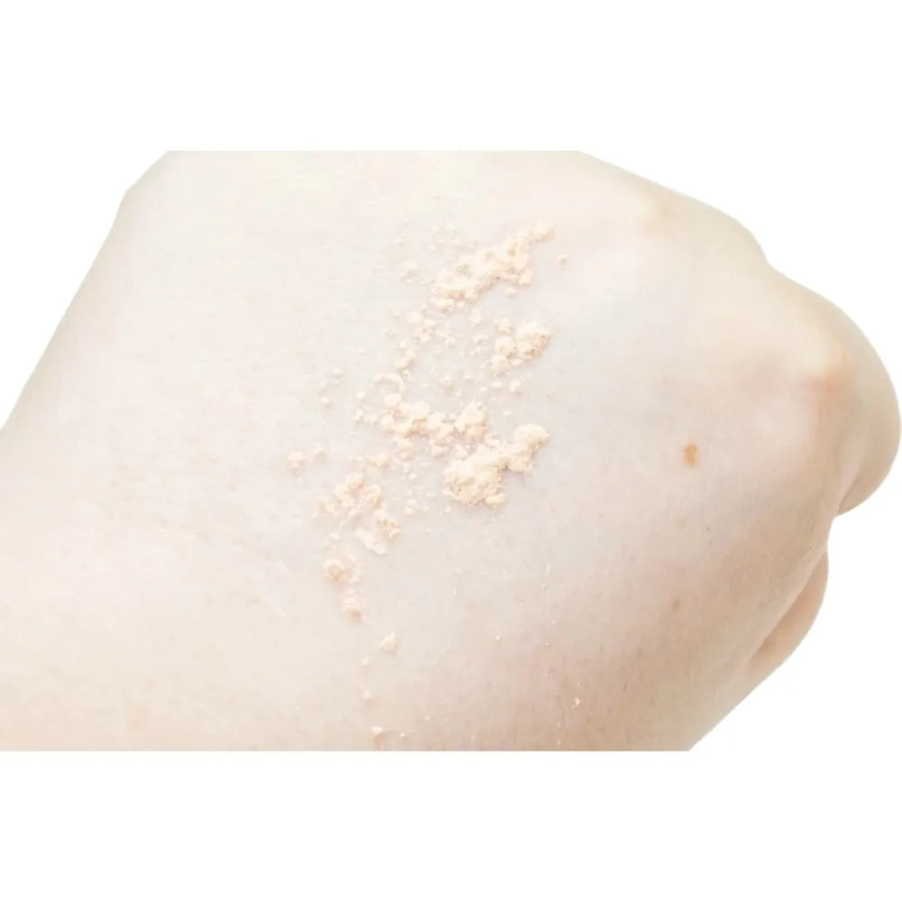 Close-up of a person's shoulder with light-colored powder on a white background