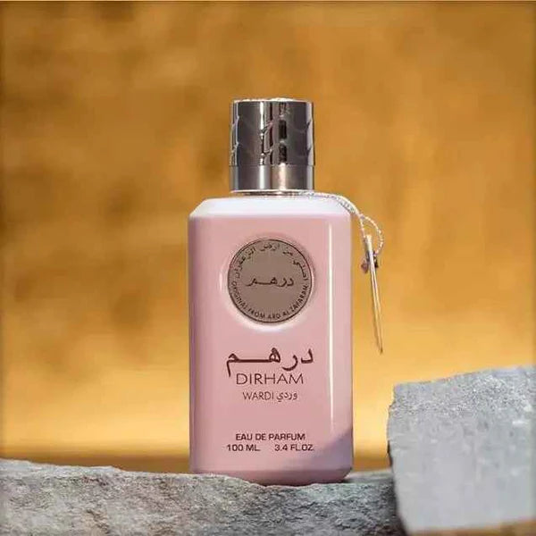 Pink perfume bottle with silver cap on a textured surface and blurred background