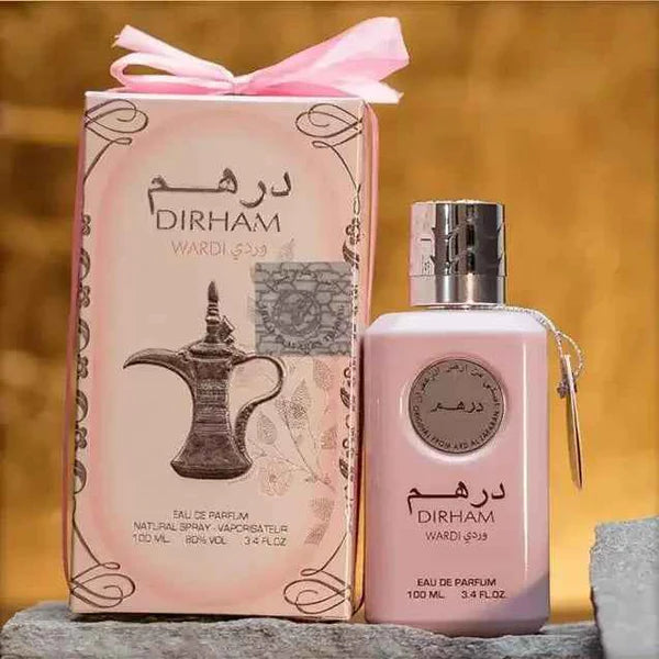 Pink perfume bottle and packaging with 'DIRHAM' branding on a wooden surface.