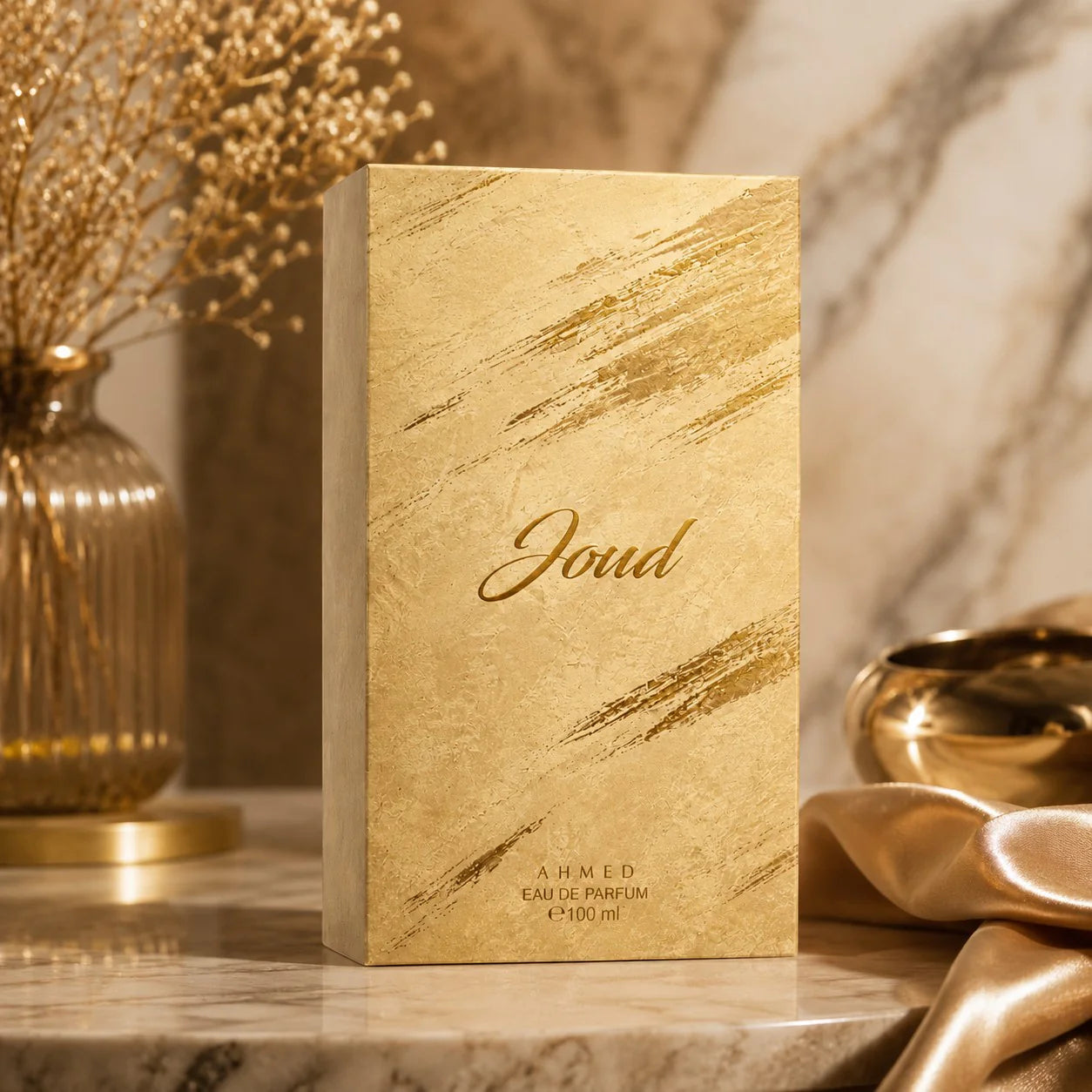 Gold Joud perfume box on a marble surface with decorative elements.